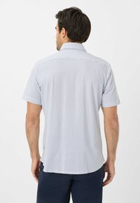 Korte mouwen shirt in lichtblauw met wit geometrisch patroon, met een puntkraag en een rechte zoom. Zachte stoftextuur.