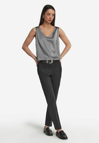 Grå satin ärmlös topp med V-hals, i kombination med svarta skräddarsydda byxor och svarta loafers. Minimal hårdvara och rena linjer.