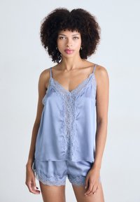 Silky light blue camisole and shorts set with intricate lace trim along the neckline and hem, featuring thin spaghetti straps and a relaxed fit.