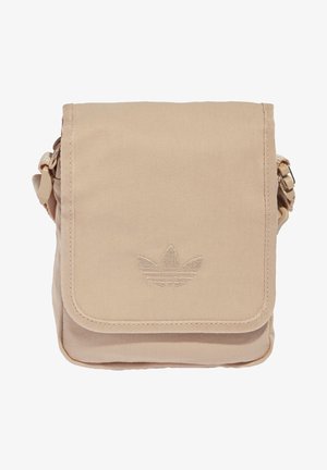 Sac bandoulière beige avec fermeture à rabat, arborant un logo Adidas Trefoil cousu et une sangle latérale ajustable.