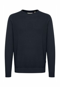 Pull tricot bleu marine avec un col rond côtelé, un corps texturé et des manches longues. Présente des coutures plates et une petite étiquette à l'ourlet.