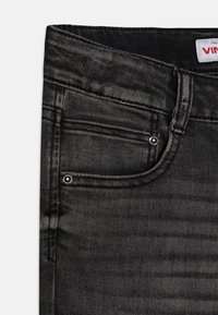 Jeans de mezclilla negra con un acabado texturizado. Presentan un diseño de cinco bolsillos, herrajes plateados y un ligero patrón desgastado a lo largo de la tela.