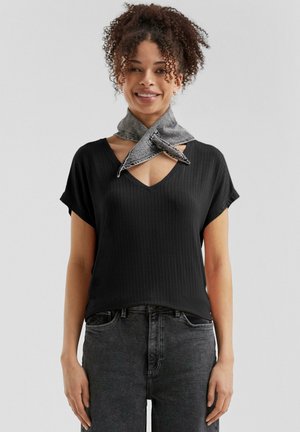 Zwarte geribbelde v-hals t-shirt met korte mouwen, gecombineerd met een grijzige denim sjaal om de hals, gedragen met donkergrijze jeans.