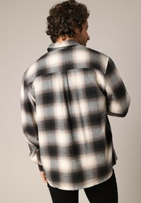 Zwart-wit geruite flanel overhemd met een relaxte pasvorm, button-down kraag en een gestructureerde stof met een licht vervaagd patroon.