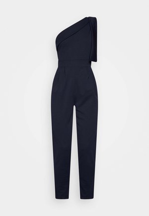 Marineblaues Ein-Schulter-Overall mit drapiertem Stoff auf einer Seite, taillierter Taille und schlanken, zulaufenden Beinen für eine figurbetonte Silhouette.