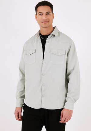 Hellegrau Button-up-Hemd mit zwei Brusttaschen, einem Kragen und einem lässigen Schnitt. Verfügt über eine glatte Textur und sichtbare Knopfdetails.
