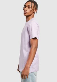 T-shirt en coton violet clair avec un col rond et des manches courtes, présentant une coupe décontractée et un petit détail imprimé à l'avant.