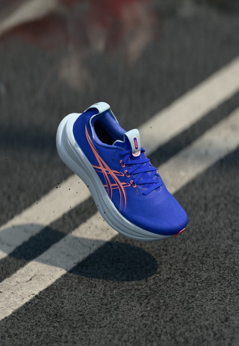 Blue athletic shoe with a textured upper, white sole, and orange accents. Features a lace closure and padded collar. Positioned above a road.