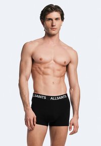 Svarta boxerkalsonger med en vit "ALLSAINTS"-logotyp på linningen. Designen är enkel och åtsittande, gjord av ett mjukt, stretchigt material.