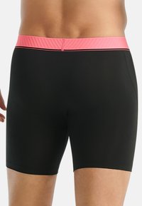 Svarta badshorts med en rosa ribbad midja, med en slät, åtsittande design och rena, enkla linjer för en strömlinjeformad look.