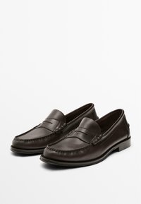Pair of dark brown leather penny loafers with stitching detail and low heel on plain white background.