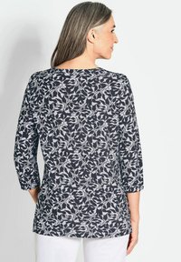 Zwart-wit bloemenpatroon top met driekwartmouwen, een ronde halslijn en een ontspannen pasvorm, gemaakt van een zachte, lichte stof.