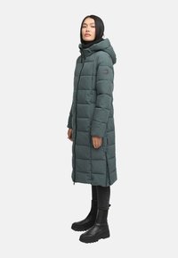 Garšs pūkains mētis tumši zaļā krāsā ar kapuci, ar rāvējslēdzēja priekšpusi un quilted rakstu. Iespējas ietver logo uzlīmi kreisajā rokā un sānu rāvējslēdzējus.