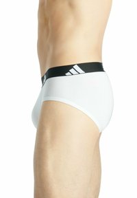Witte boxershorts met een zwarte tailleband met een wit adidas-logo. De boxershorts hebben een gladde textuur en een aansluitend ontwerp.