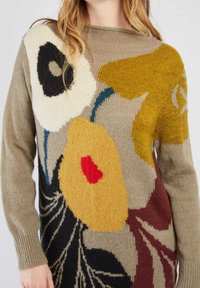 Pull en tricot avec un motif floral en beige, jaune moutarde, rouge et noir. Encolure ronde et poignets côtelés soulignent les manches.