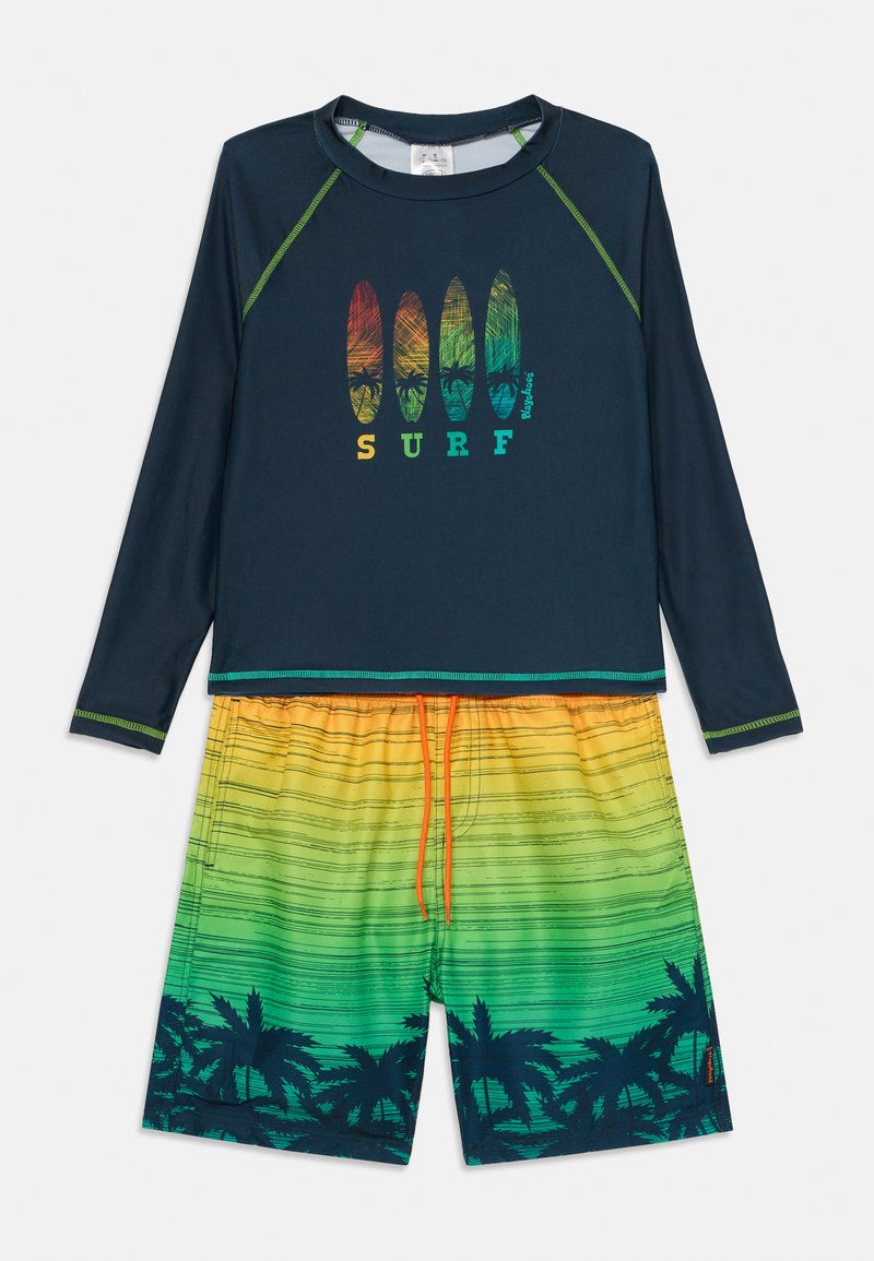 Dlhý rukáv námorníckej modrej rash guard s zeleným prešívaním, s grafikou surfboardu. Šortky so žlto-zeleným gradientom a vzorom palmových stromov s šnúrkou.