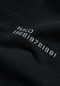Svart tyg med en slät textur som har vittryckt text: "HALO 196819721981" i olika teckensnittsstorlekar och stilar.