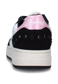 Sneaker bianco e nero con un'accente rosa sul tallone, dotata di dettagli perforati, design semplice e suola bianca spessa.