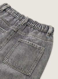 Elastické, vysoko pásové šedé denimové nohavice s elastickým pásom, s dvoma zadnými vreckami a hladkou textúrou. Obsahujú viditeľné švy.
