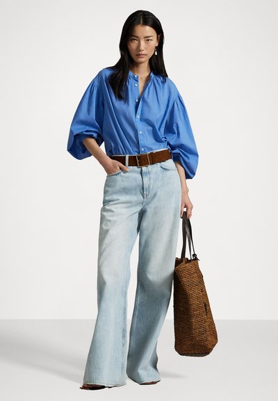 Light blue oversized button-up shirt with puff sleeves, paired with light denim wide-leg jeans and a brown woven tote bag.