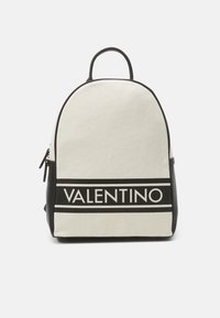 Mochila de lienzo en crema con acentos negros; presenta una forma redondeada, un mango superior y el logotipo de 'VALENTINO' destacado de manera prominente.