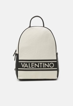 Mochila de lienzo en crema con acentos negros; presenta una forma redondeada, un mango superior y el logotipo de 'VALENTINO' destacado de manera prominente.