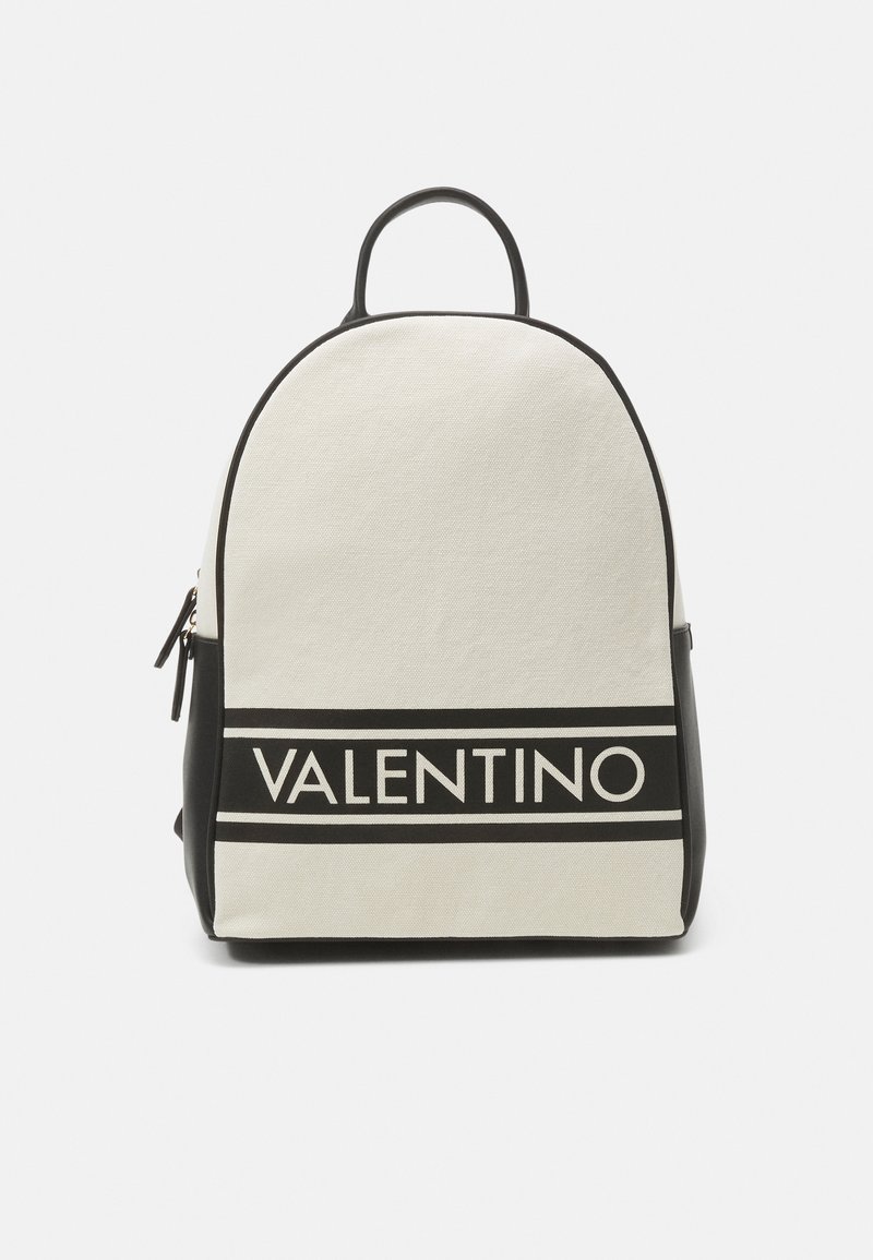 Mochila de lienzo en crema con acentos negros; presenta una forma redondeada, un mango superior y el logotipo de 'VALENTINO' destacado de manera prominente.