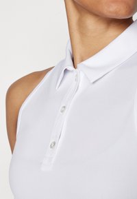Polo shirt bianco senza maniche realizzato in tessuto texturizzato, con una chiusura con bottoni e colletto strutturato. Design pulito e semplice.