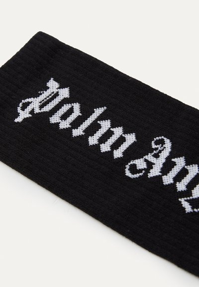 Fascia nera a coste con il testo "Palm Angel" in lettere gotiche bianche a contrasto. Texture liscia con una vestibilità aderente.