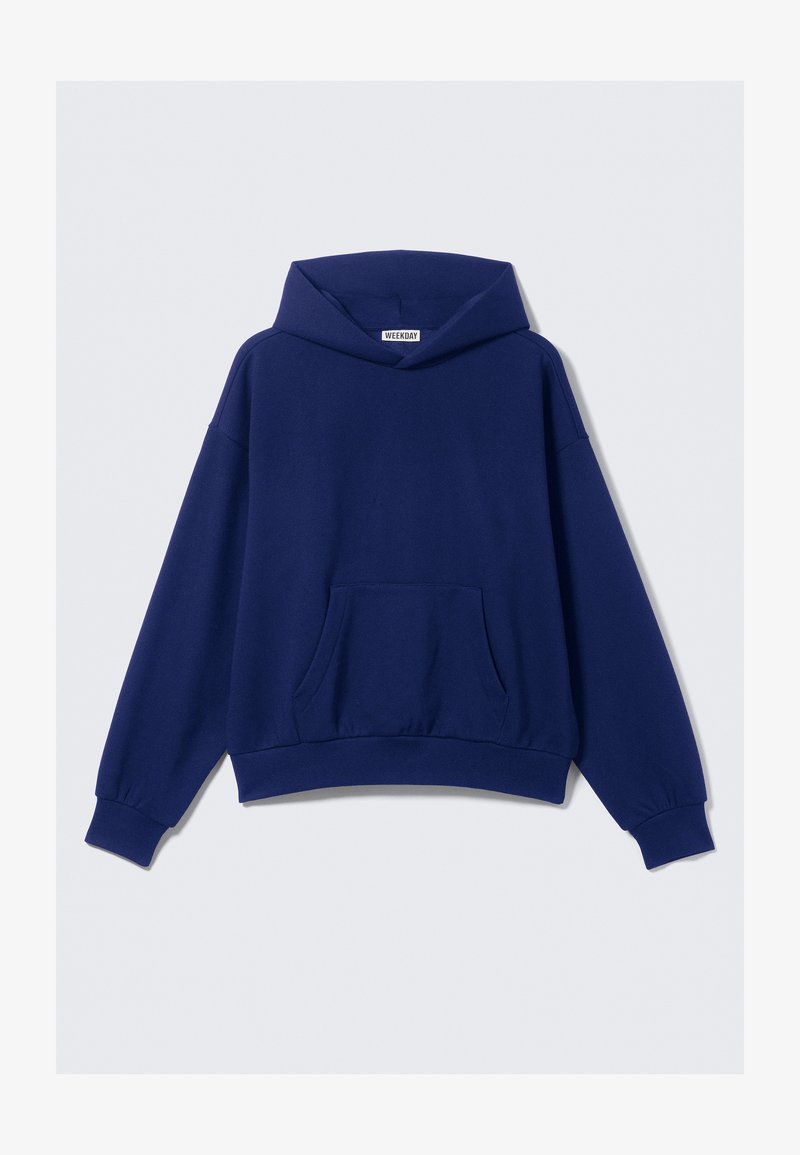 Ναυτικό μπλε υπερμεγέθες φούτερ από μαλακό ύφασμα, με φαρδύ καπέλο, μπροστινή τσέπη και ριμπ μανσέτες και στρίφωμα. Απλός σχεδιασμός, χωρίς μοτίβα.