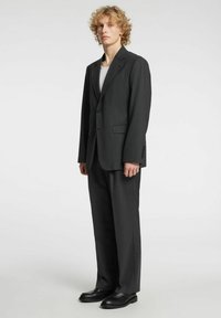 Completo due pezzi grigio scuro con blazer monopetto e pantaloni sartoriali, realizzato in tessuto liscio con due tasche frontali e design minimalista.