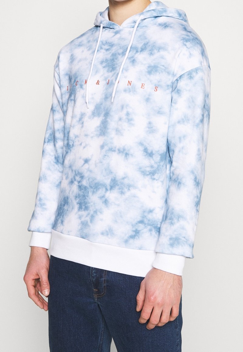 Bluza z kapturem w niebiesko-białym wzorze tie-dye, z białym sznurkiem i prążkowanymi mankietami. Tekst logo w kolorze koralowym na klatce piersiowej.