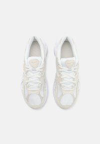 Bílé tenisky s horní částí z meshe a kůže, mají tkaničky, kulatou špičku, polstrovaný jazyk a texturované detaily v světle béžové barvě.