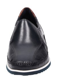 Schwarzer Leder-Schlupfschuh mit abgerundetem Zeh, kontrastierenden braunen Akzenten an der Ferse, weißer Zwischensohle und strukturiertem Nähen entlang der Kante.