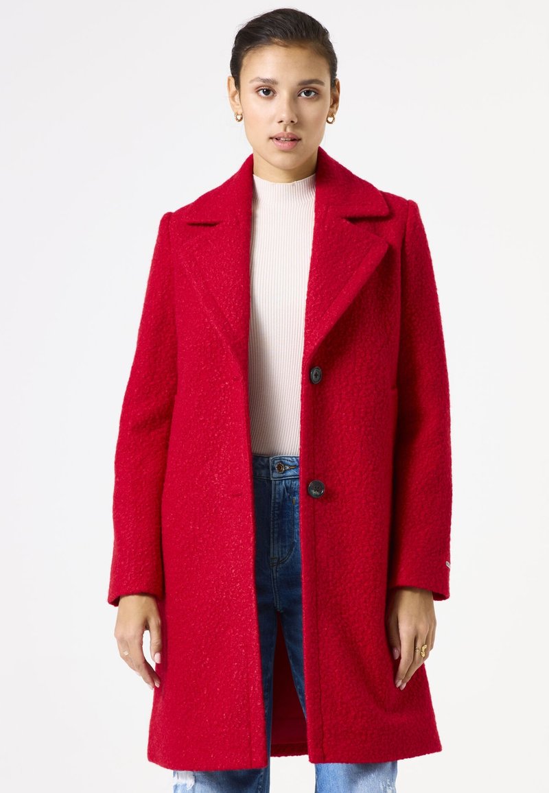 Manteau en mélange de laine rouge avec une finition texturée, larges revers et deux boutons. Le design comprend des manches longues et une coupe mi-longue.