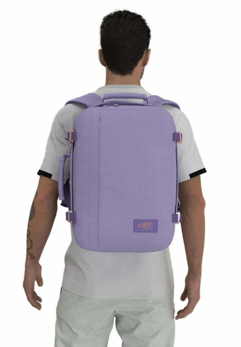 Zaino rettangolare viola con spallacci regolabili, manico superiore e tasche laterali. Realizzato in tessuto resistente con dettagli di marca.