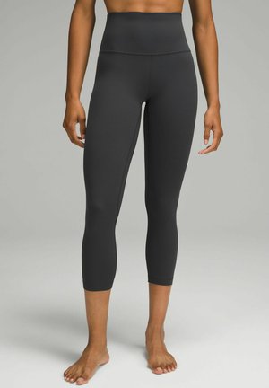 Czarne legginsy wysokiej talii wykonane z elastycznego, gładkiego materiału; krótki krój w jednolitym kolorze z minimalnymi detalami szwów.