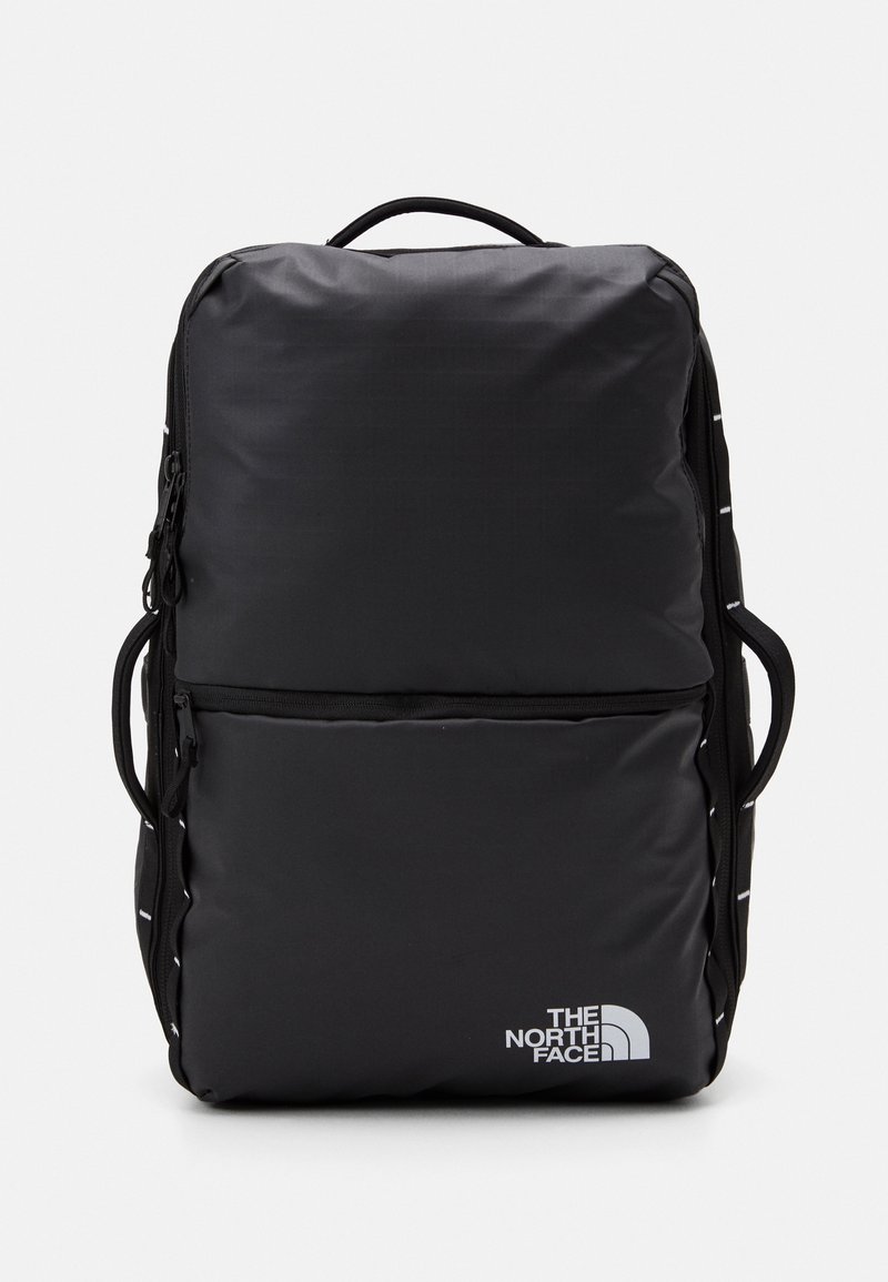 Svart ryggsäck med rektangulär form, tillverkad av slitstarkt tyg. Har två fickor med dragkedja och en vit logotyp på framsidan.