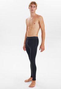 Black thermal leggings with a snug fit and a narrow waistband featuring a gray accent. Made from a smooth, stretchy material.