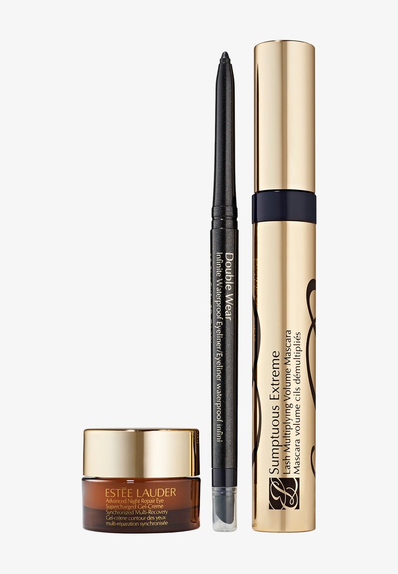 Estée Lauder øyekremkrukke, svart uttrekkbar eyelinerpenn og gullmascara i vertikal rekkefølge på hvit bakgrunn.