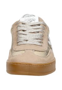 Beige suede sneaker with metallic accents, round toe, and textured laces. Features a gum rubber sole and side logo detailing.