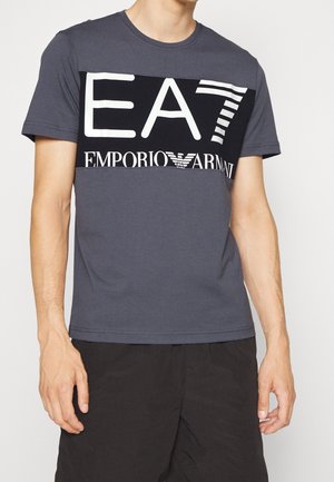 Grå bomuld T-shirt med et fedt sort-hvidt logodesign, inklusive teksten "EAT" og "EMPORIO ARMANI". Korte ærmer, rund hals.