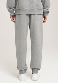 Szare dresy w luźnym kroju, wykonane z miękkiego materiału. Posiadają elastyczny pas i małą tylną kieszeń. W połączeniu z białymi trampkami.