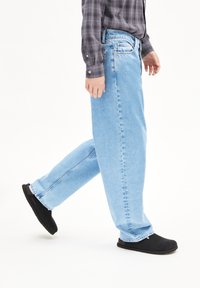 Lichtblauwe rechte spijkerbroek met een vervaagde afwerking. De stof is denim en beschikt over vijf zakken en een knoopsluiting. Gemaakt in combinatie met zwarte instappers.