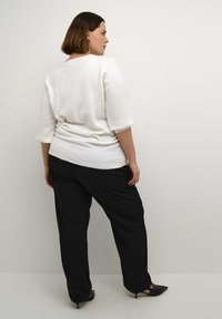 White knitted sweater with three-quarter sleeves, paired with black wide-leg trousers and black pointed shoes, viewed from the back.