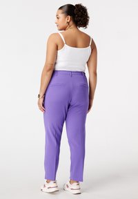 Paars op maat gemaakte broek met een slim fit, voorzien van een middelhoge tailleband en achterzakken, gecombineerd met een witte tanktop en witte sneakers.