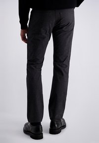 Donkergrijze broek van een gestructureerde stof, slim fit, met twee achterzakken, gecombineerd met zwarte leren schoenen met decoratieve accenten.