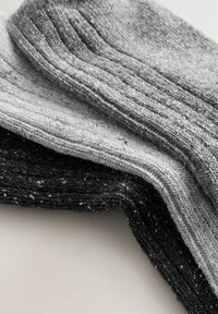 Hallitatud sokid halli ja musta tooni, ribikujunduse ja täpilise detailiga, üksteise peal kokku pandud.