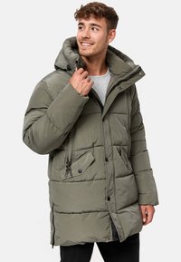 Padded olive green parka jacket with a hood, front zip, snap buttons, two front pockets, and drawstring accents. Textured fabric finish.