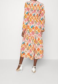 Langærmet, mellemlang kjole med et farverigt geometrisk mønster i lyserøde, orange og blå nuancer. Elastisk talje og flæsekjole.